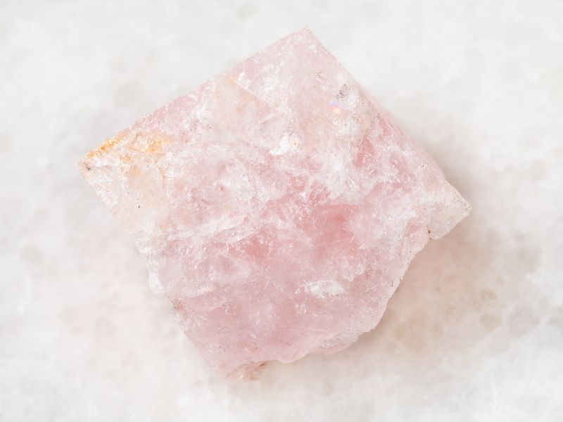 macro shooting of natural mineral rock specimen - rough crystal of morganite (pink beryl) gemstone on white marble background from Mozambique-摩根石功效